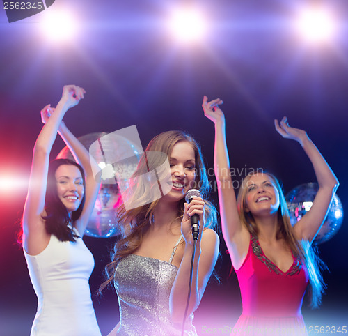 Image of three smiling women dancing and singing karaoke