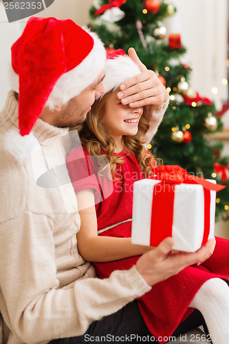 Image of smiling father surprises daughter with gift box