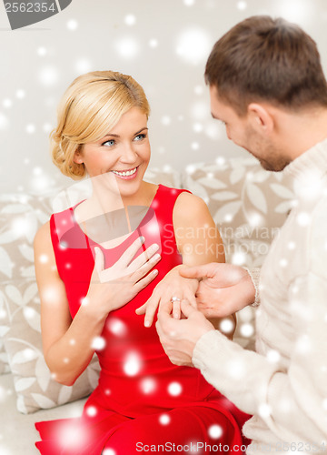 Image of romantic man proposing to a woman in red dress