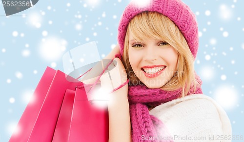 Image of woman in pink hat and scarf with shopping bags