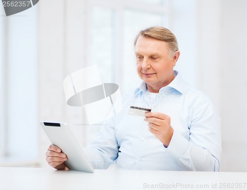 Image of old man with tablet pc and credit card at home