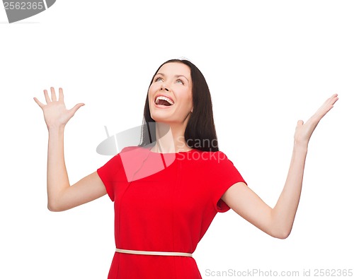 Image of smiling young woman in red dress with hands up