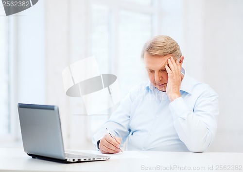 Image of old man filling a form at home