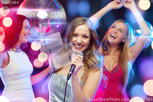 Image of three smiling women dancing and singing karaoke