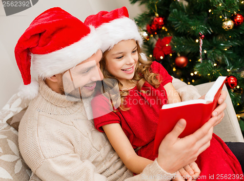 Image of smiling father and daughter reading book