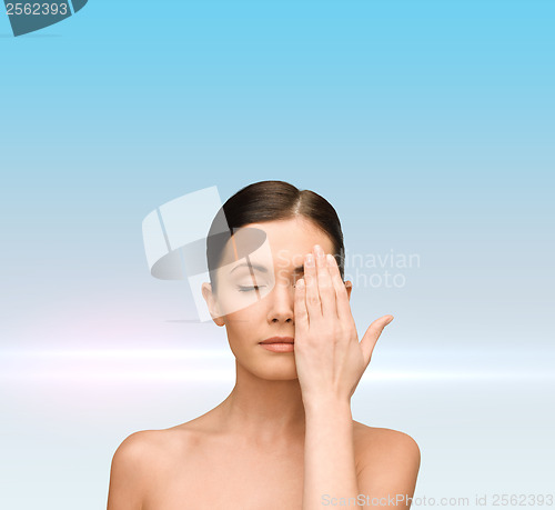 Image of calm young woman covering face with hand
