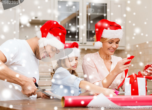 Image of smiling family in santa helper hats with gift box