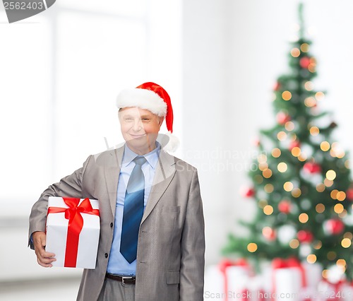 Image of smiling man in suit and santa helper hat with gift