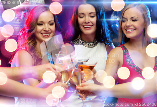 Image of three smiling women with cocktails in club