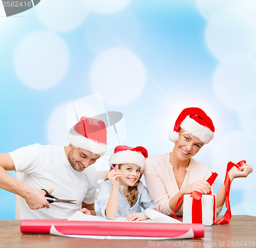 Image of smiling family in santa helper hats with gift box