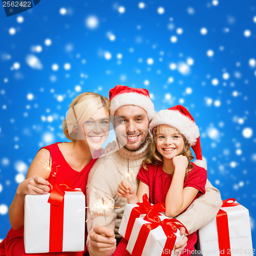 Image of smiling family holding gift boxes and sparkles