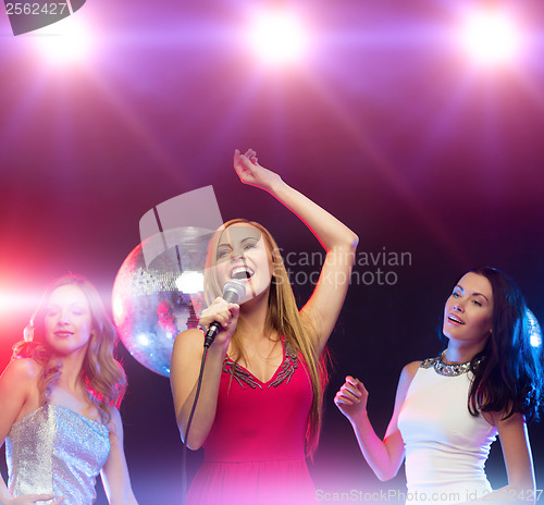 Image of three smiling women dancing and singing karaoke