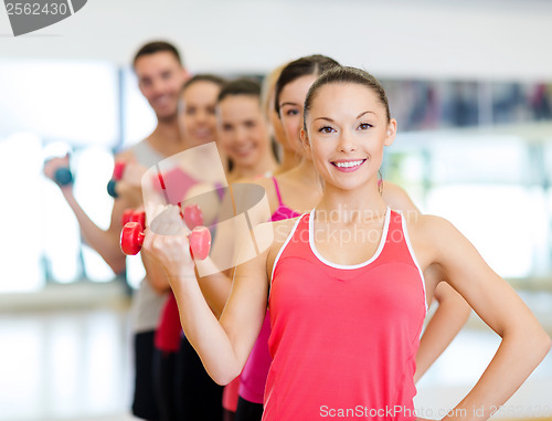 Image of group of smiling people with dumbbells in the gym