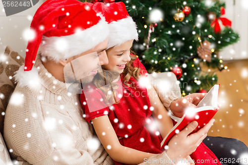 Image of smiling father and daughter reading book