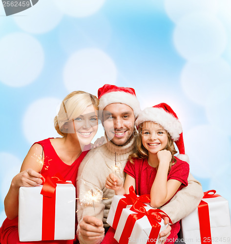 Image of smiling family holding gift boxes and sparkles