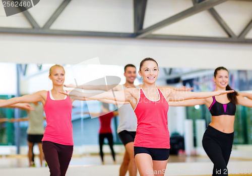 Image of group of smiling people exercising in the gym