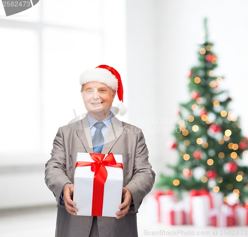 Image of smiling man in suit and santa helper hat with gift