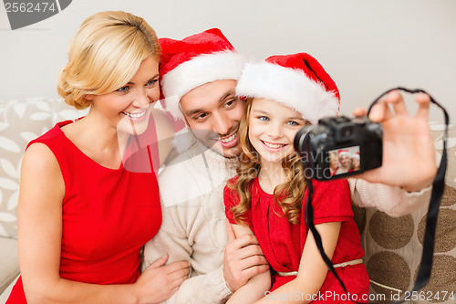 Image of smiling family in santa helper hats taking picture