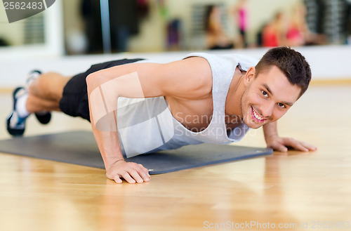 Image of smiling man doing push-ups in the gym