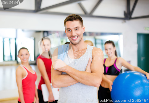 Image of smiling man standing in front of the group in gym