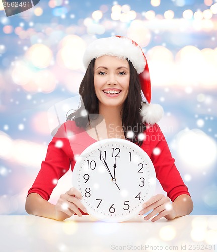 Image of woman in santa helper hat with clock showing 12