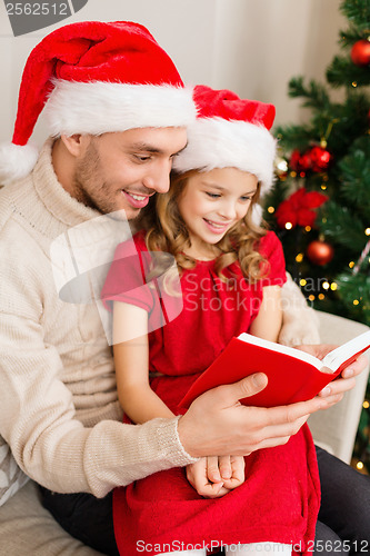 Image of smiling father and daughter reading book