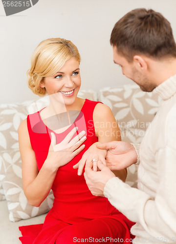 Image of romantic man proposing to a woman in red dress