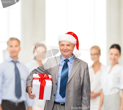 Image of smiling man in suit and santa helper hat with gift