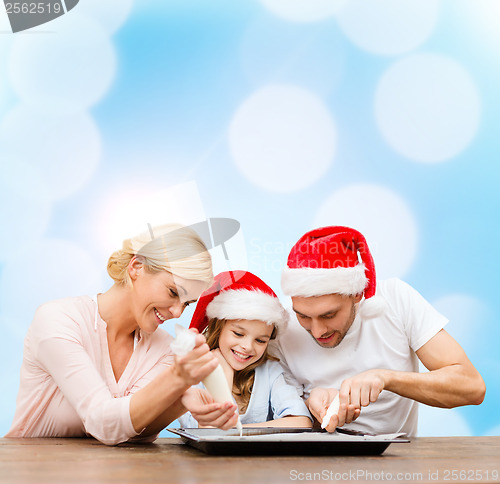 Image of happy family in santa helper hats making cookies