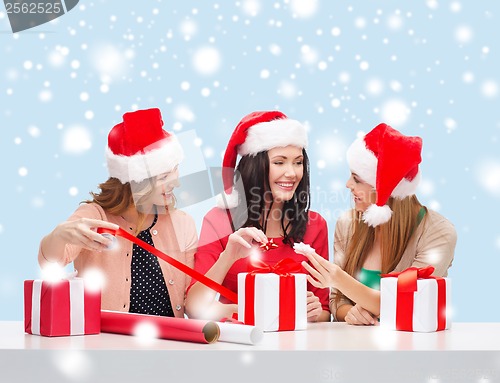 Image of smiling women in santa helper hats with gift boxes