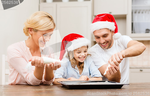 Image of happy family in santa helper hats making cookies