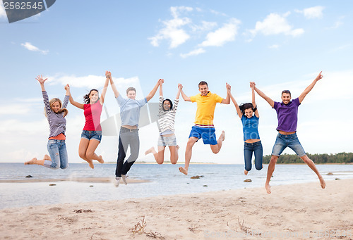 Image of group of friends jumping on the beach