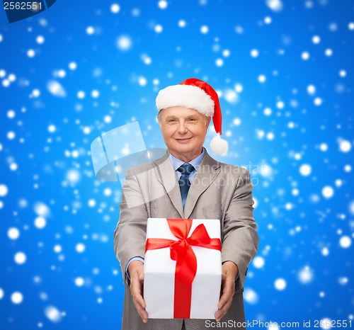 Image of smiling man in suit and santa helper hat with gift