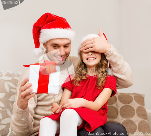 Image of smiling father surprises daughter with gift box