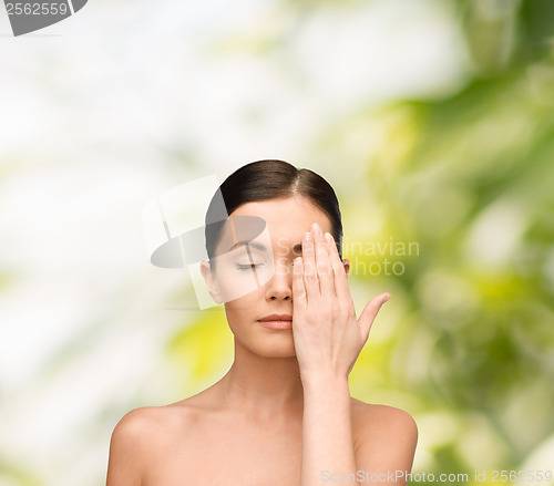Image of calm young woman covering face with hand