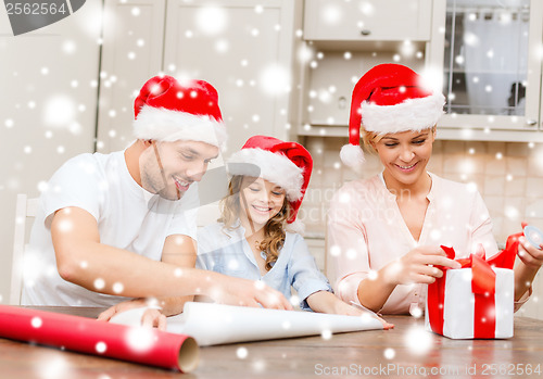 Image of smiling family in santa helper hats with gift box