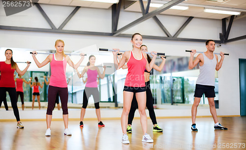 Image of group of smiling people working out with barbells