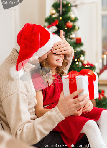 Image of smiling father surprises daughter with gift box