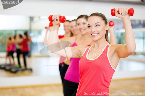 Image of group of smiling people working out with dumbbells