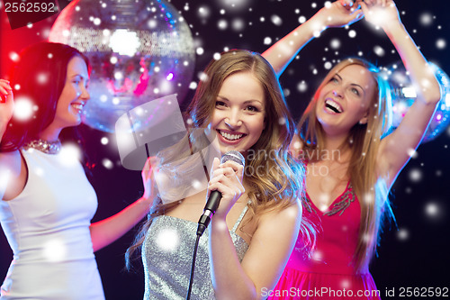 Image of three smiling women dancing and singing karaoke