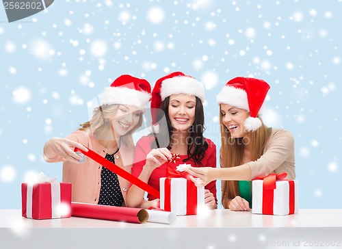 Image of smiling women in santa helper hats with gift boxes