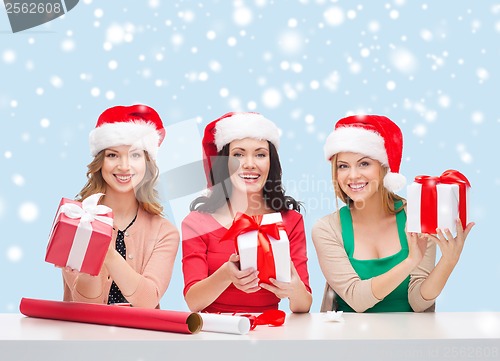 Image of smiling women in santa helper hats with gift boxes