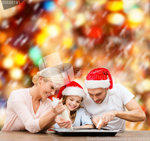 Image of happy family in santa helper hats making cookies