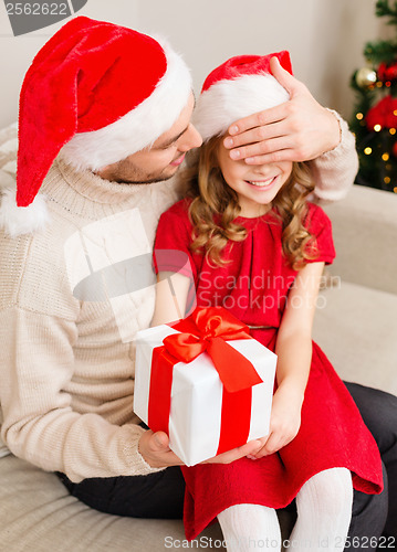 Image of smiling father surprises daughter with gift box