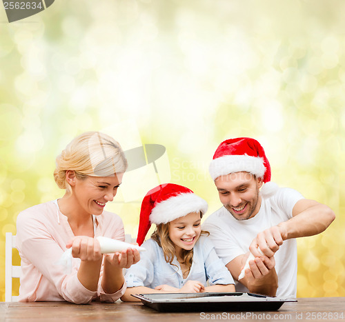 Image of happy family in santa helper hats making cookies