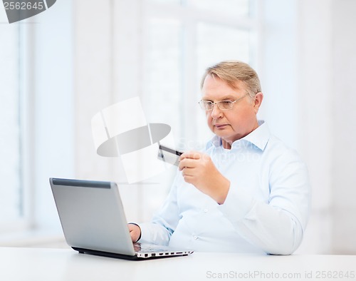 Image of old man with laptop and credit card at home