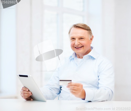 Image of old man with tablet pc and credit card at home