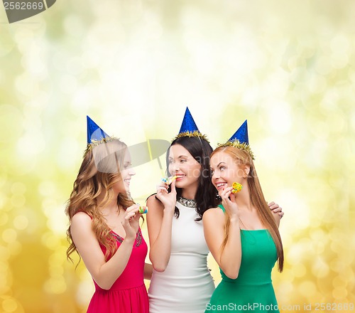 Image of three smiling women in hats blowing favor horns