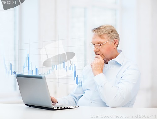 Image of old man in eyeglasses working with laptop at home