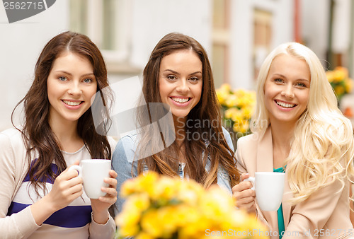 Image of three beautiful girls drinking coffee in cafe